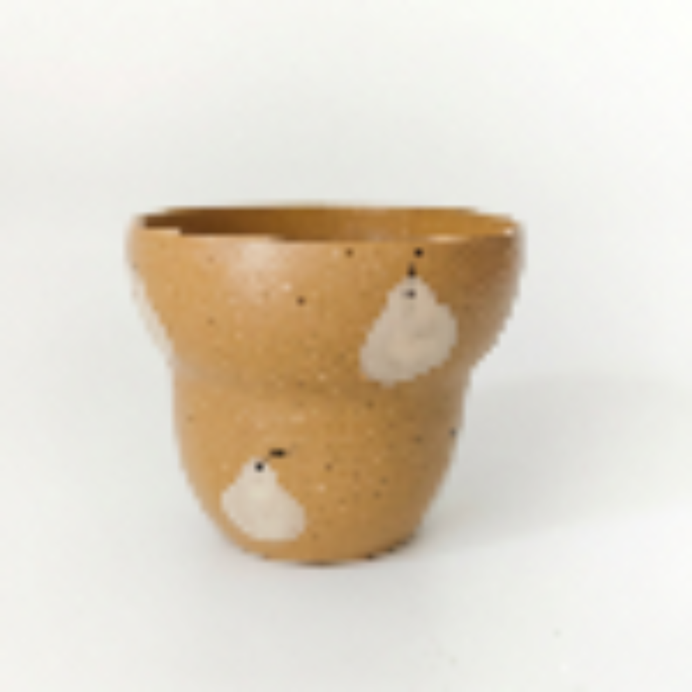 A straight-on studio shot of a stepped, handleless ceramic cup by Kove Ceramics on a clean white background, showcasing its glossy mustard yellow glaze, natural clay speckles, and hand-painted white pear motif.
