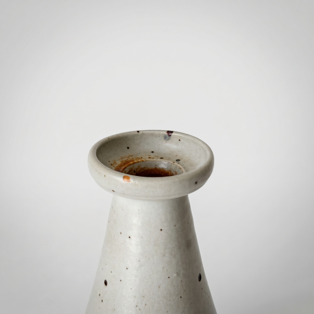 A close-up detail shot focusing on the flared rim and narrow opening of a wabi-sabi style speckled ceramic bud vase by Kove Ceramics, showcasing the unique rustic glaze details and earthy speckles.